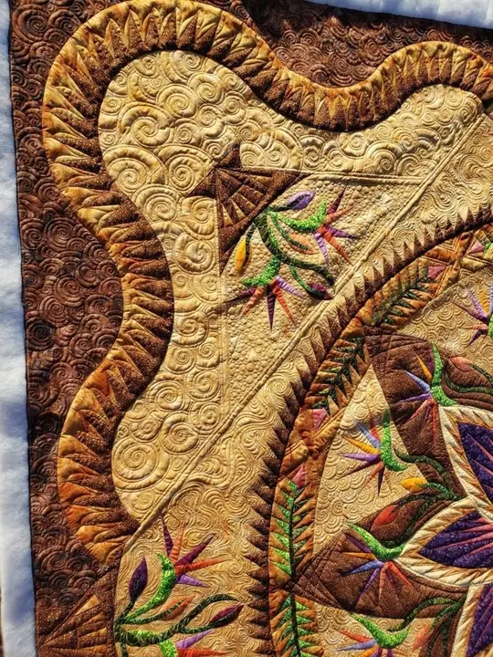 Gold and amber feathered and paisley quilting in graduated thread