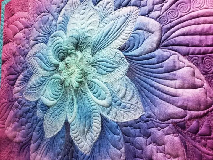 Radiant flower quilt in teal and magenta on a purple ground